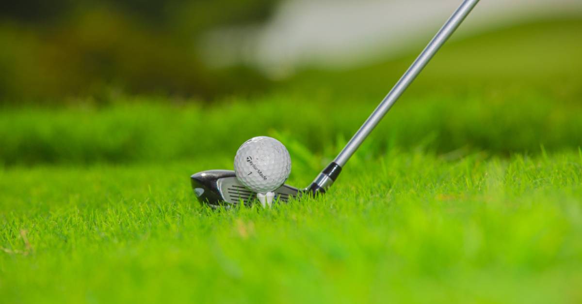 A-golf-ball-on-the-tee-with-a-club-positioned-for-a-swing-on-a-green-course