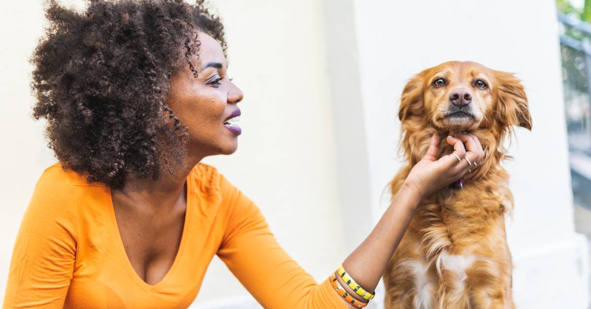 Woman-in-an-orange-shirt-petting-a-fluffy-brown-dog